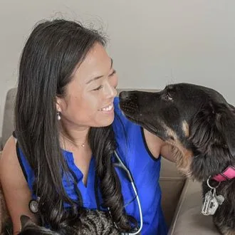 Dr. Mac smiling as a black-and-tan dog leans in close